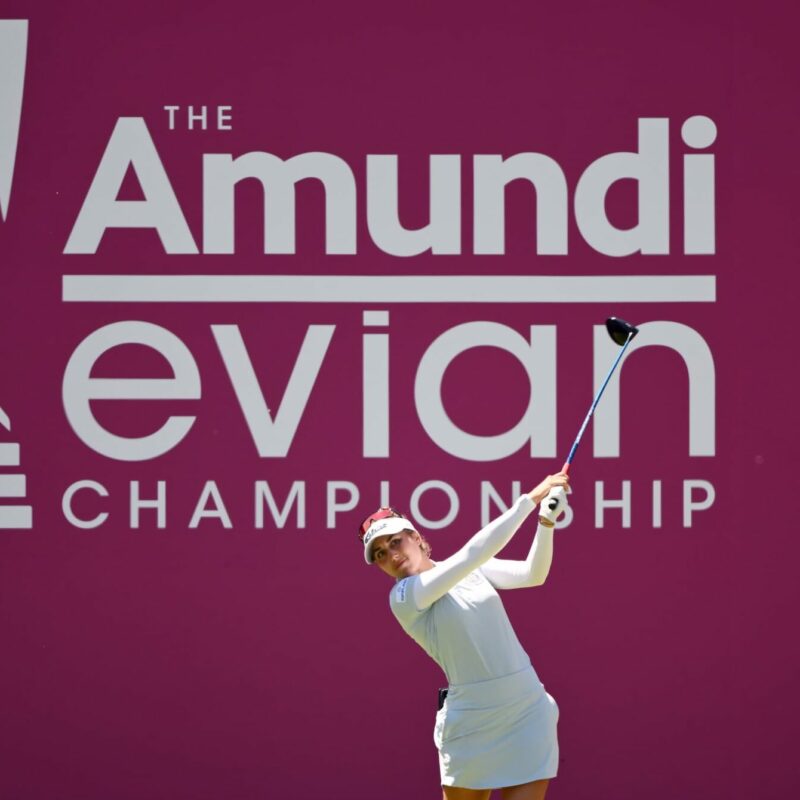 Une joueuse de golf drive devant le logo de l'Amundi Évian Championship