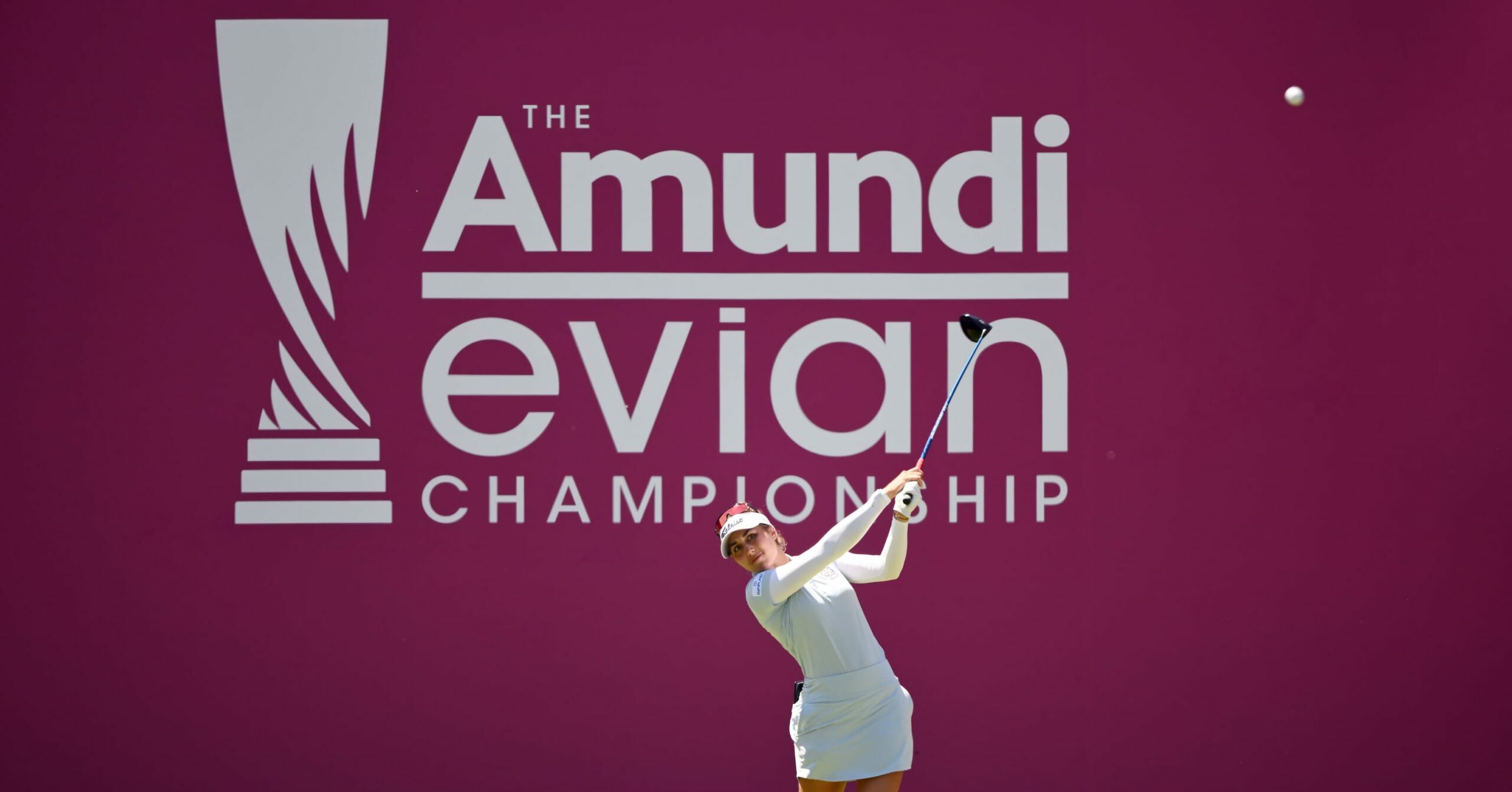Une joueuse de golf drive devant le logo de l'Amundi Évian Championship